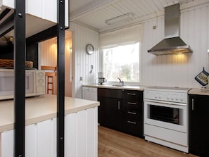 Cocina compacta con electrodomésticos blancos, ventana con vistas y un reloj en la pared.