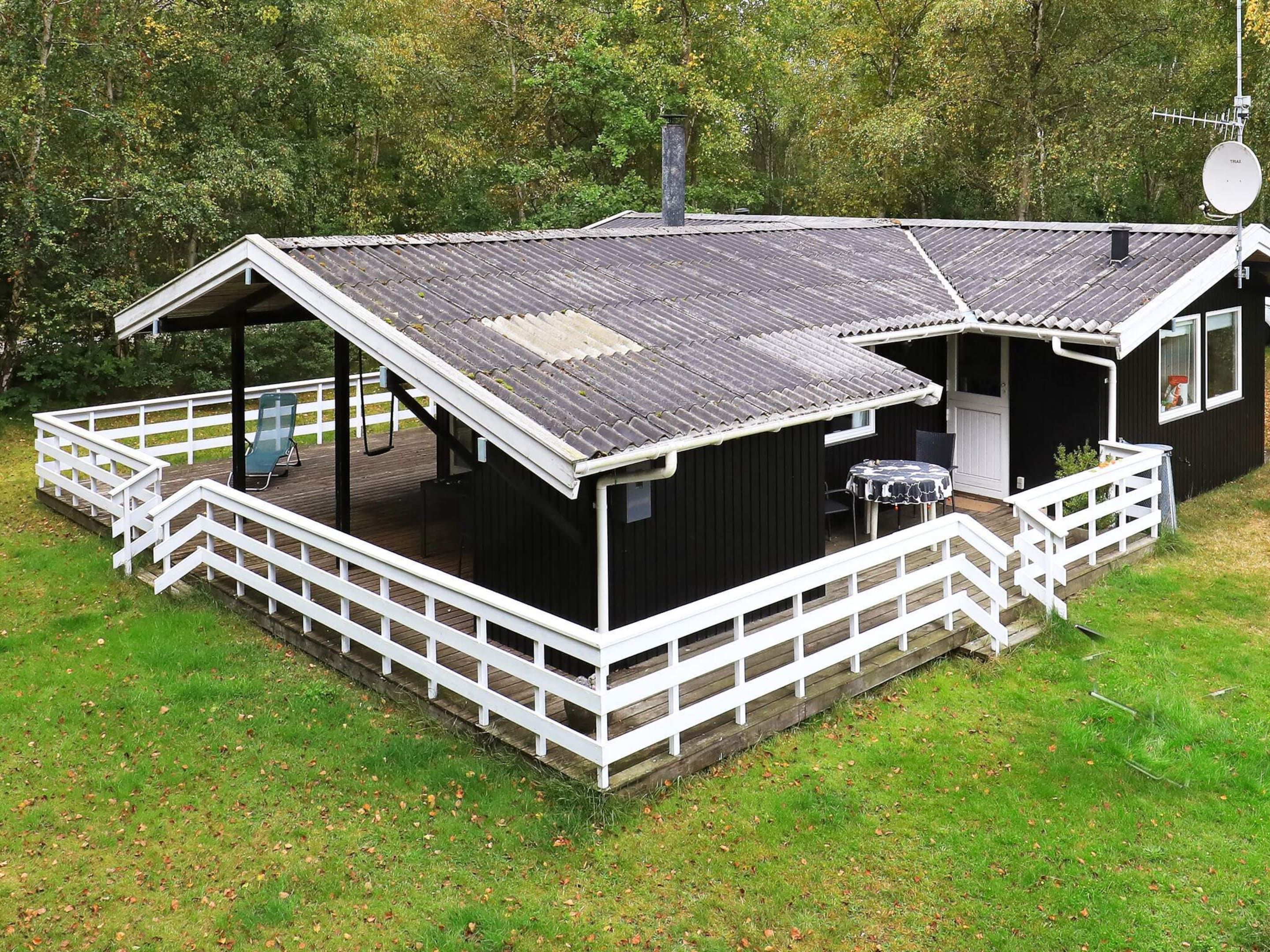 A black cabin with a white deck, a covered seating area, and a satellite dish.