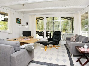 A modern living room with a sofa, a coffee table, a TV, and a chair. - 6 Person Holiday Home in Laeso (Læsø)