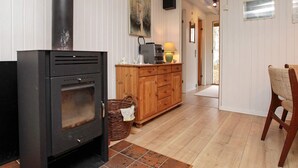 A cozy living room with a wood-burning stove, a wooden cabinet, a wicker basket, and a chair.