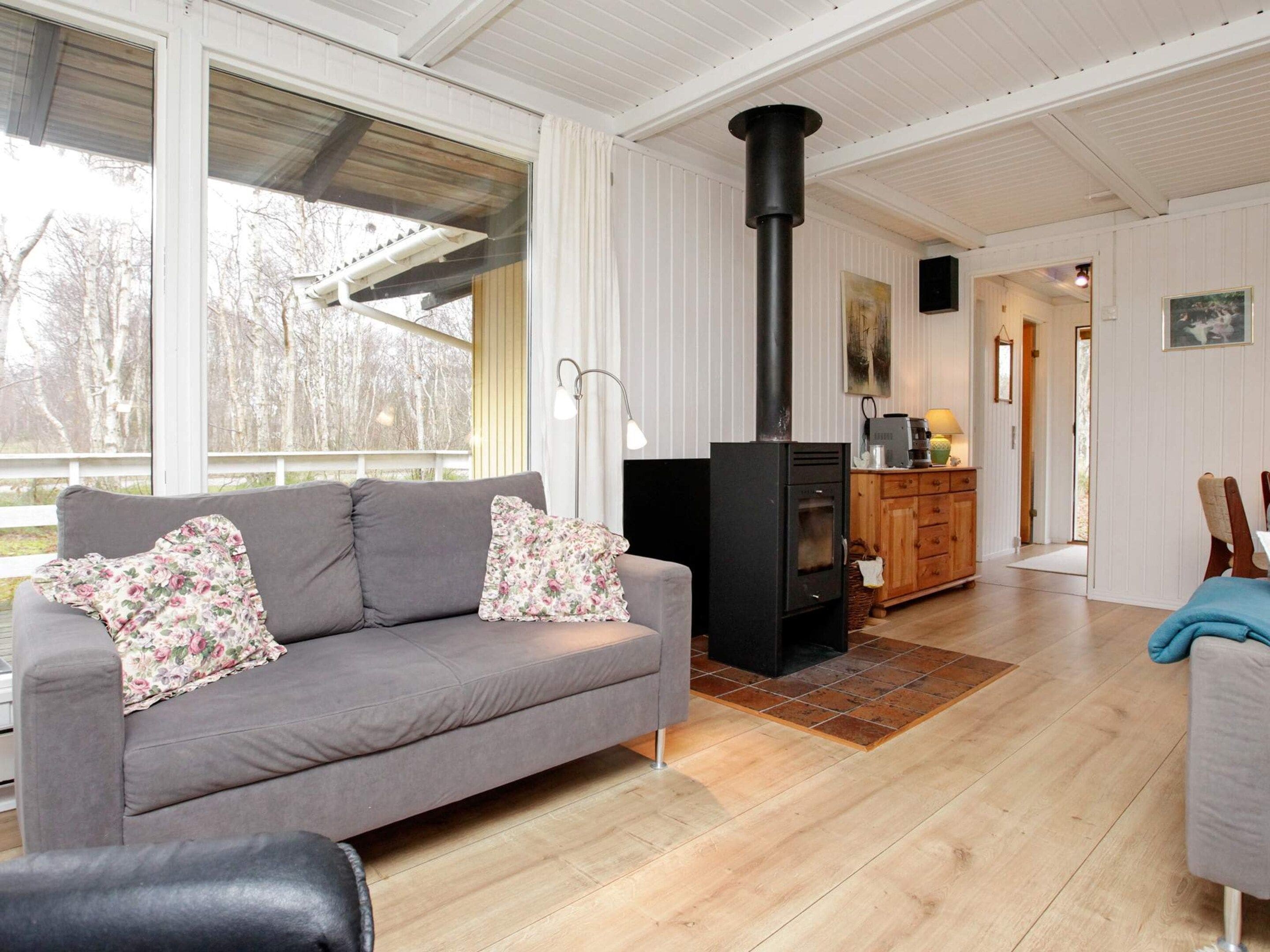 Un salon chaleureux avec un canapé, une cheminée et une vue sur l’extérieur.