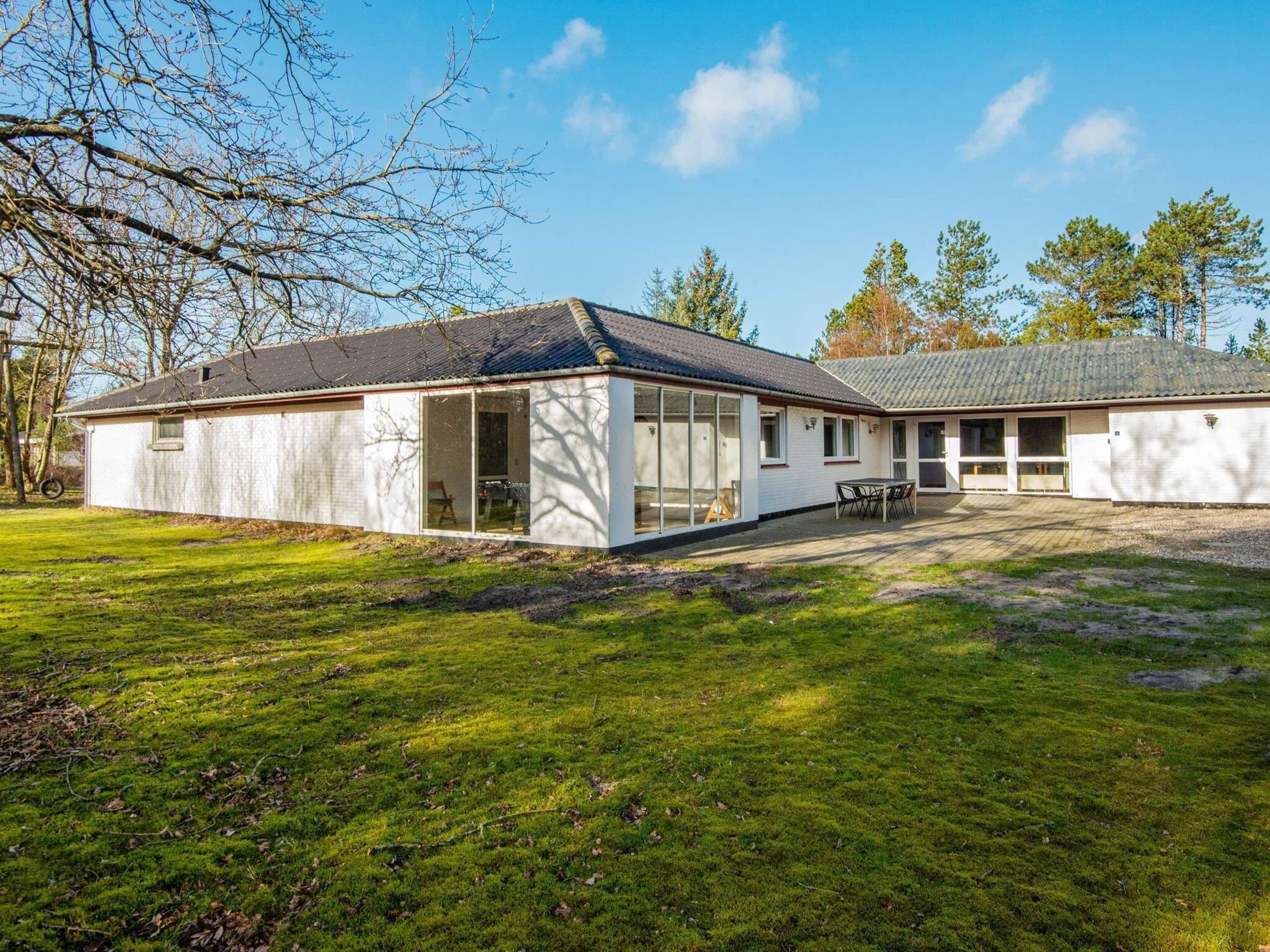 A single-story building with a large glass door entrance, a covered patio area, and a grassy yard.