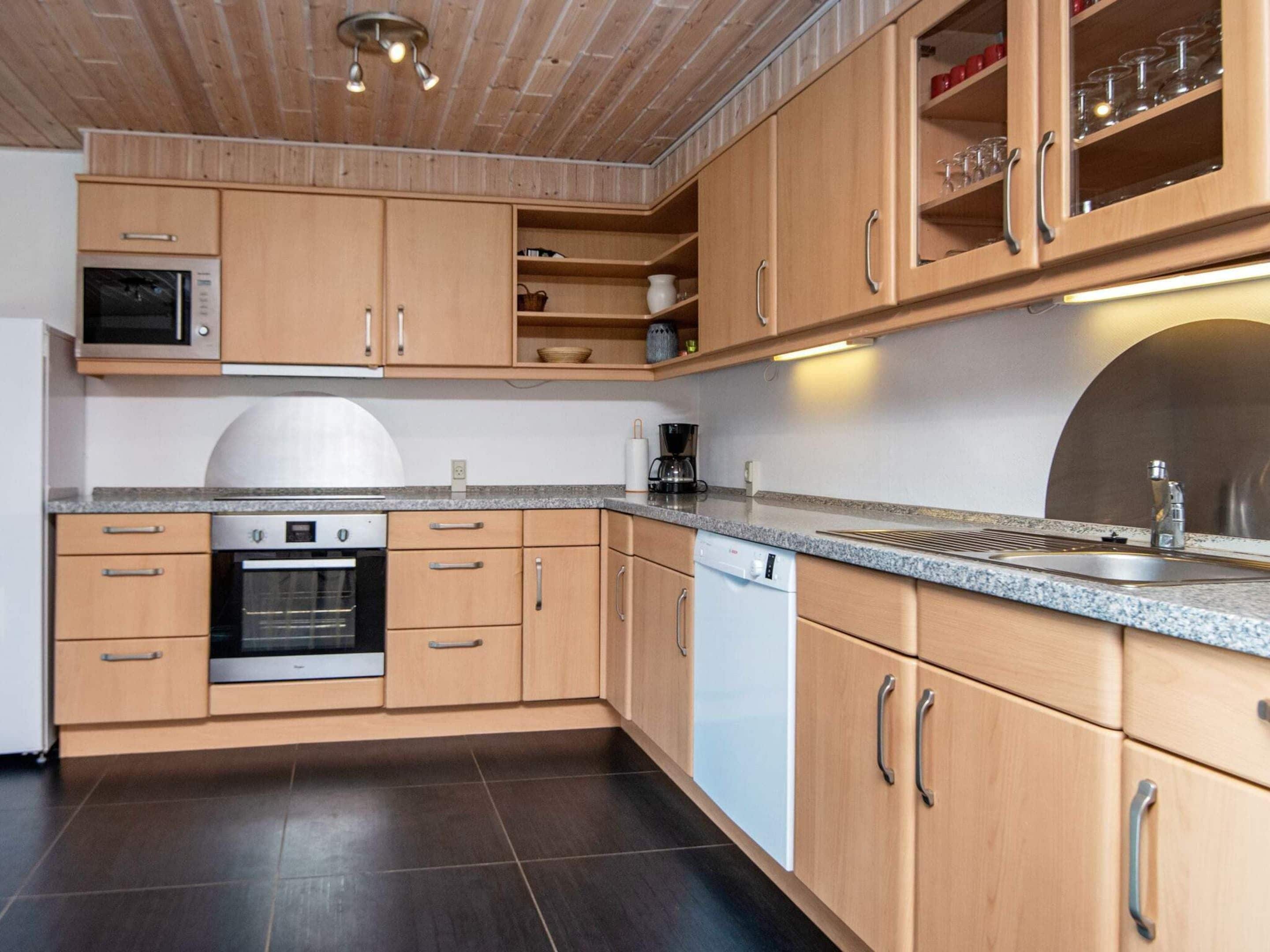 A modern kitchen with wooden cabinets, stainless steel appliances, and a granite countertop.