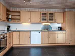 A modern kitchen with wooden cabinets, a dishwasher, and a granite countertop.