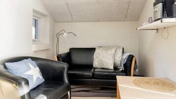 A compact living space with a black leather sofa, a small table, and a lamp.