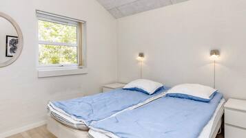 A bedroom with two beds, a window, and wall-mounted lights.