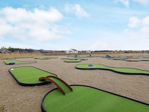 Un campo de mini golf con varias áreas de juego verdes y un cielo despejado.