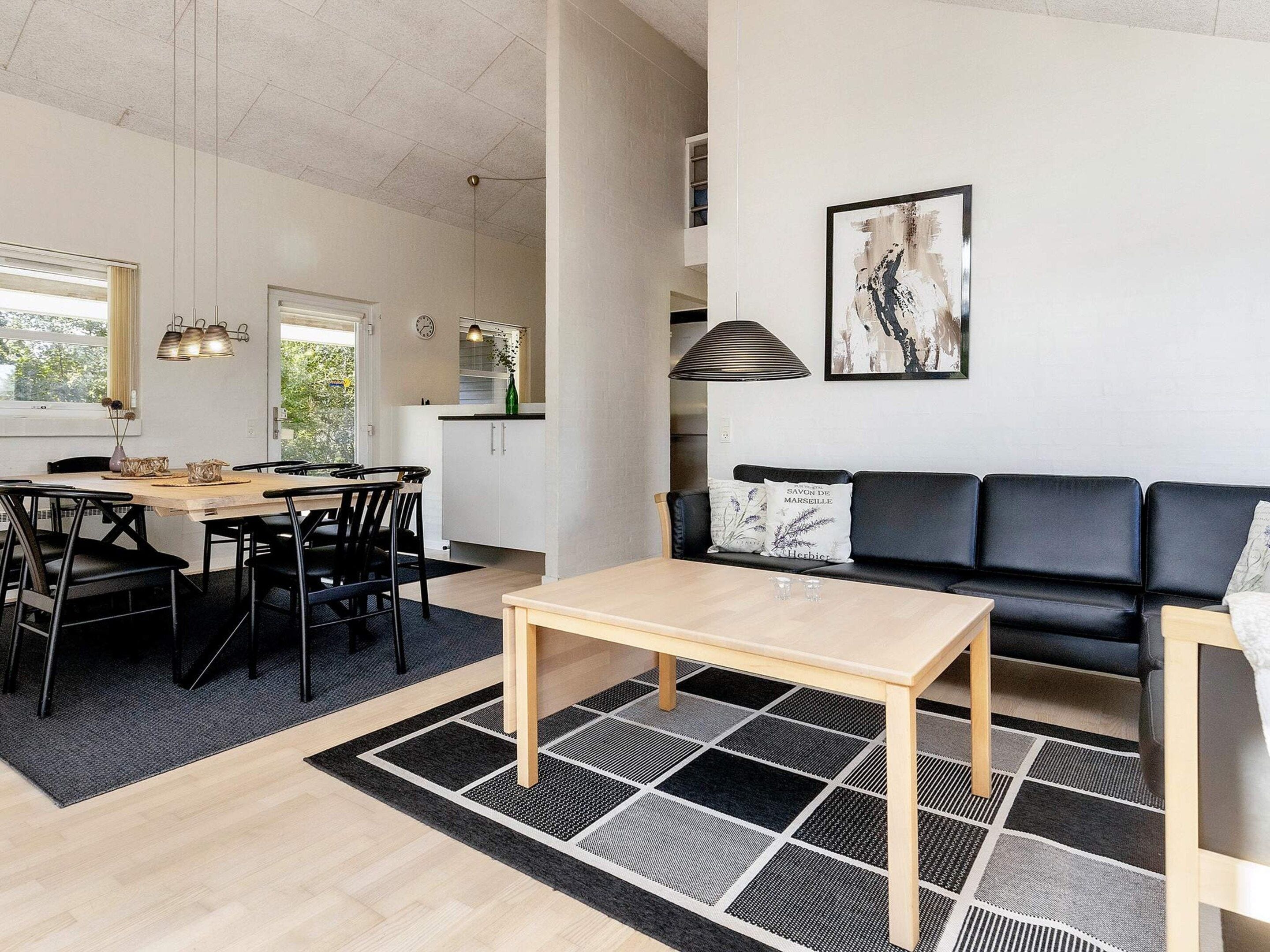 Un espace de vie moderne comprenant un coin repas, un canapé et une cuisine en arrière-plan.