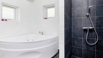 A modern bathroom with a freestanding bathtub, a shower with a handheld showerhead, and two windows with pink curtains.
