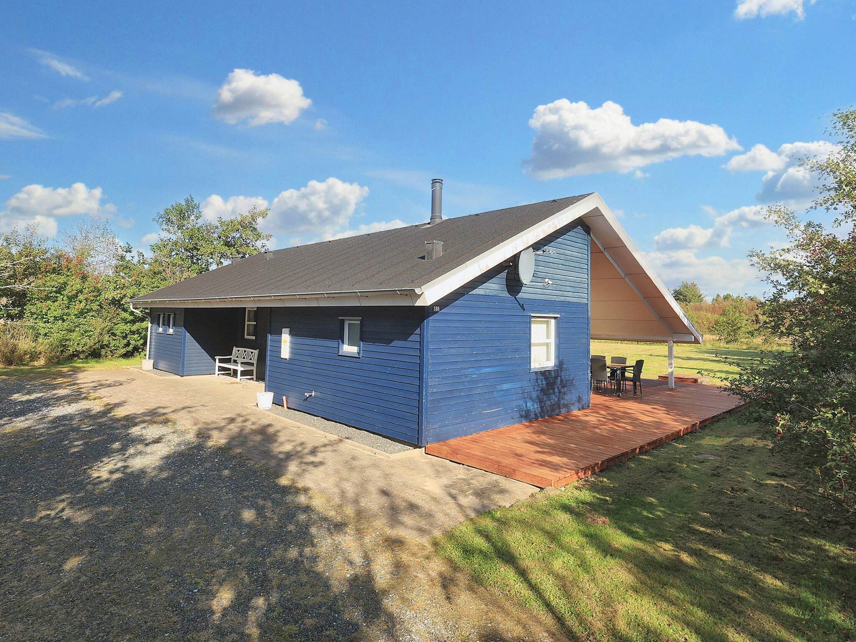 Un bâtiment bleu d’un seul étage, doté d’un toit en pente, d’un patio couvert et d’une all ée gravillonnée.
