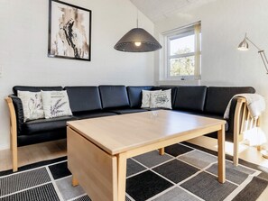 A modern living room with a black sectional sofa, a wooden coffee table, and a black and white patterned rug. - 5 Star Holiday Home in Brovst (Brovst)