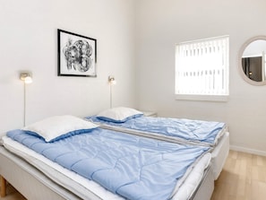 A bedroom with a bed, a framed picture on the wall, a window with blinds, and a round mirror. - 5 Star Holiday Home in Brovst (Brovst)