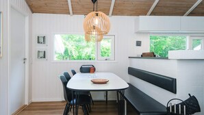 A modern dining area with a white table, black chairs, a wooden ceiling, and a hanging light fixture. - 4 Star Holiday Home in Bindslev (Bindslev)