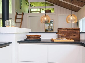 A kitchen with white cabinets, a wooden counter, wicker baskets, and hanging pendant lights. - 4 Star Holiday Home in Bindslev (Bindslev)
