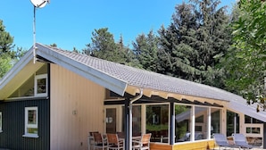 A modern house with a covered patio, a deck, and a satellite dish.