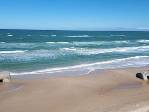 A beach with waves and a clear sky.