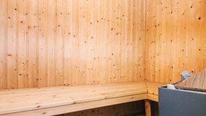 A wooden sauna with a bench and a small table.
