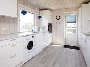 Enjoy a kitchen with washing machine, window with outside view, and door to adjacent room.