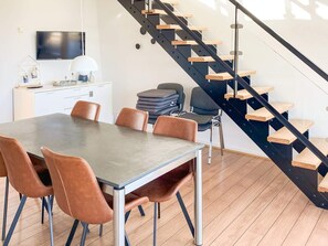 Una cocina moderna con comedor, una escalera de madera y un televisor de pantalla plana montado en la pared.