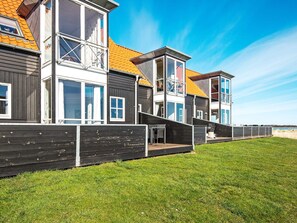 Een meerlaags woongebouw met een plat dak, grote ramen en een houten terras.