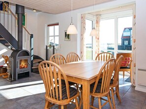 A dining area with a wooden table and chairs, a fireplace, and a staircase.