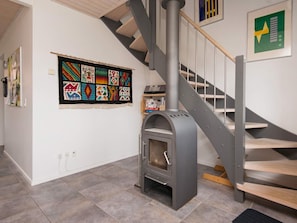 Un interior moderno con una escalera, una obra de arte colgada en la pared y un hogar a leña.