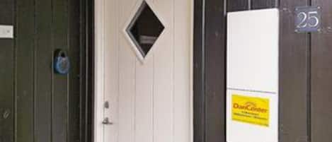 A door with a small window, a white sign with yellow text, and a number '25' on the wall.
