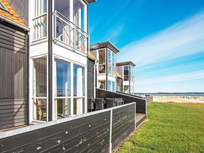 A modern multi-story house with large windows and a balcony, located near a beach. - 5 Star Holiday Home in Juelsminde (Juelsminde)