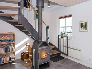 Een modern interieur met een houtkachel, een trap en een boekenplank.
