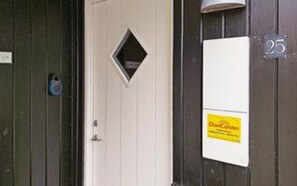 A door with a small window, a white sign with yellow text, and a number '25' on the wall. - 5 Star Holiday Home in Juelsminde (Juelsminde)