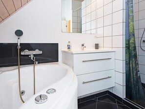 A modern bathroom with a freestanding bathtub, a handheld showerhead, a mirror, and a sink with a faucet. - 5 Star Holiday Home in Juelsminde (Juelsminde)