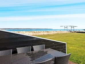 A deck with a view of the sea, a grassy area, and a metal structure in the distance. - 5 Star Holiday Home in Juelsminde (Juelsminde)
