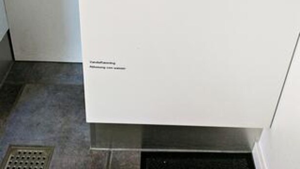 Ett vitt kök med en köksfläkt och ett ventilationssystem, båda i rostfritt stål.