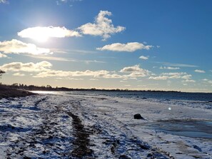 A beach with a clear sky, a visible path, and a distant shoreline. - 6 Person Holiday Home in Vaeggerlose (Vaeggerlose)