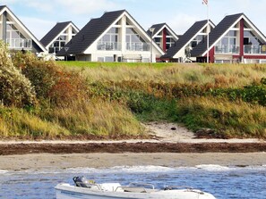A row of beach houses with large windows and a boat on the shore. - Holiday Home in Wendtorf (Wendtorf)