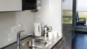 A modern kitchen with a stainless steel sink, a Bosch coffee maker, and a microwave above it. - Holiday Home in Wendtorf (Wendtorf)