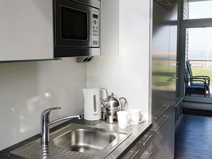 A modern kitchen with a stainless steel sink, a Bosch coffee maker, and a microwave above it. - Holiday Home in Wendtorf (Wendtorf)
