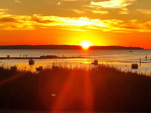 A sunset over a body of water with boats and a distant shoreline. - Holiday Home in Wendtorf (Wendtorf)