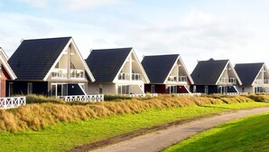 A row of modern beach houses with sloped roofs, white railings, and a pathway leading through the property. - Holiday Home in Wendtorf (Wendtorf)