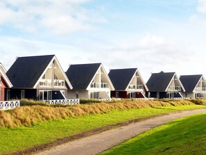 A row of modern beach houses with sloped roofs, white railings, and a pathway leading through the property. - Holiday Home in Wendtorf (Wendtorf)