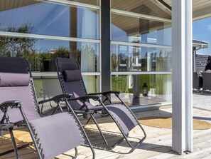 Un espace extérieur abrité comprenant deux fauteuils inclinables et une terrasse en bois.