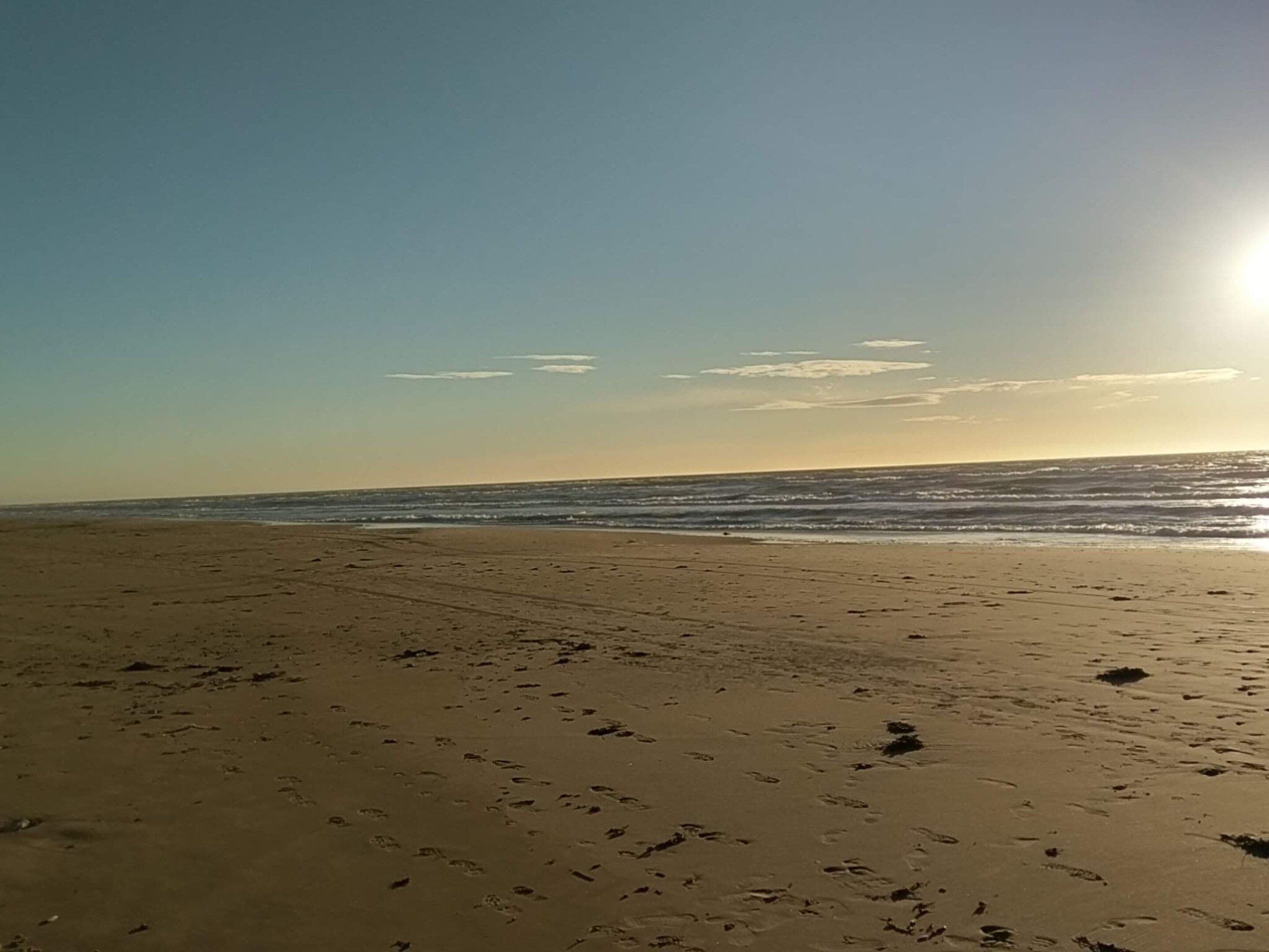 A beach with footprints and the ocean in the background.