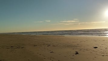 A beach with footprints and the ocean in the background.