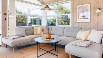 A modern living room with a sectional sofa, a round coffee table, and a large window providing natural light.