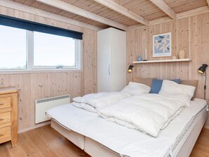 Une chambre à coucher comprenant un lit, une commode, un radiateur, une fenêtre donnant sur un beau paysage et une étagère ornée d’objets décoratifs.