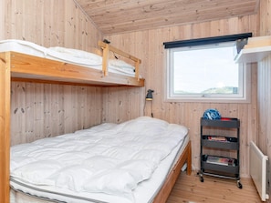 A bunk bed with a wooden frame and white bedding, a small desk with a lamp, and a window with a view. - 5 Star Holiday Home in Hjorring (Hjørring)