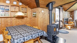 A cozy cabin interior with a wooden interior, a dining table, chairs, a stove, and a television. - 6 Person Holiday Home in Vestervig (Vestervig)