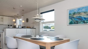 A modern kitchen with white cabinets, a wooden dining table, and four white chairs. - 6 Person Holiday Home in Allingabro-by Traum (Allingåbro)
