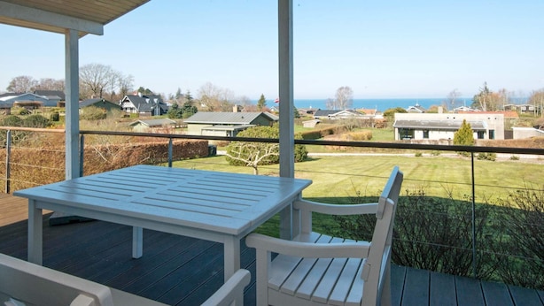 A covered outdoor area with a table and chairs, overlooking a residential neighborhood and the sea. - 6 Person Holiday Home in Allingabro-by Traum (Allingåbro)