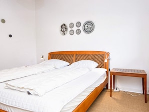 A neatly made bed with a wooden headboard and a bedside table with a keyboard.